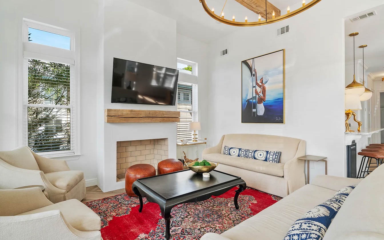 Sink into plush cream sofas while golden chandelier light dances overhead. Your cozy fireplace creates perfect ambiance for memorable evenings together.