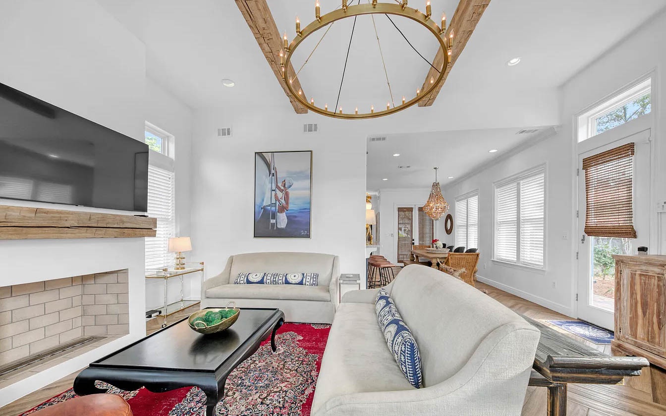 Unwind in your open-plan living space, where soaring ceilings and elegant chandelier create a luxurious coastal retreat.