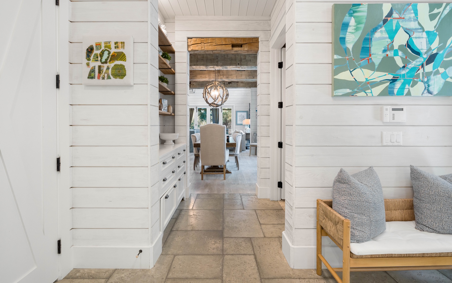 Relax in your bright coastal retreat with shiplap walls, artistic touches, and cozy seating flowing into dining spaces.
