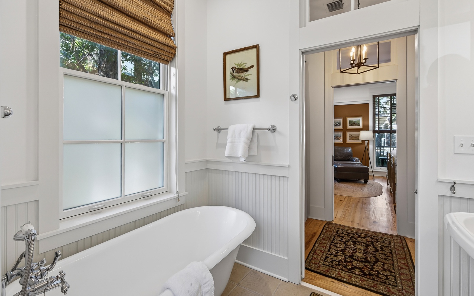 Your private bathroom sanctuary features a soaking tub where you can unwind while natural light streams through bamboo blinds.
