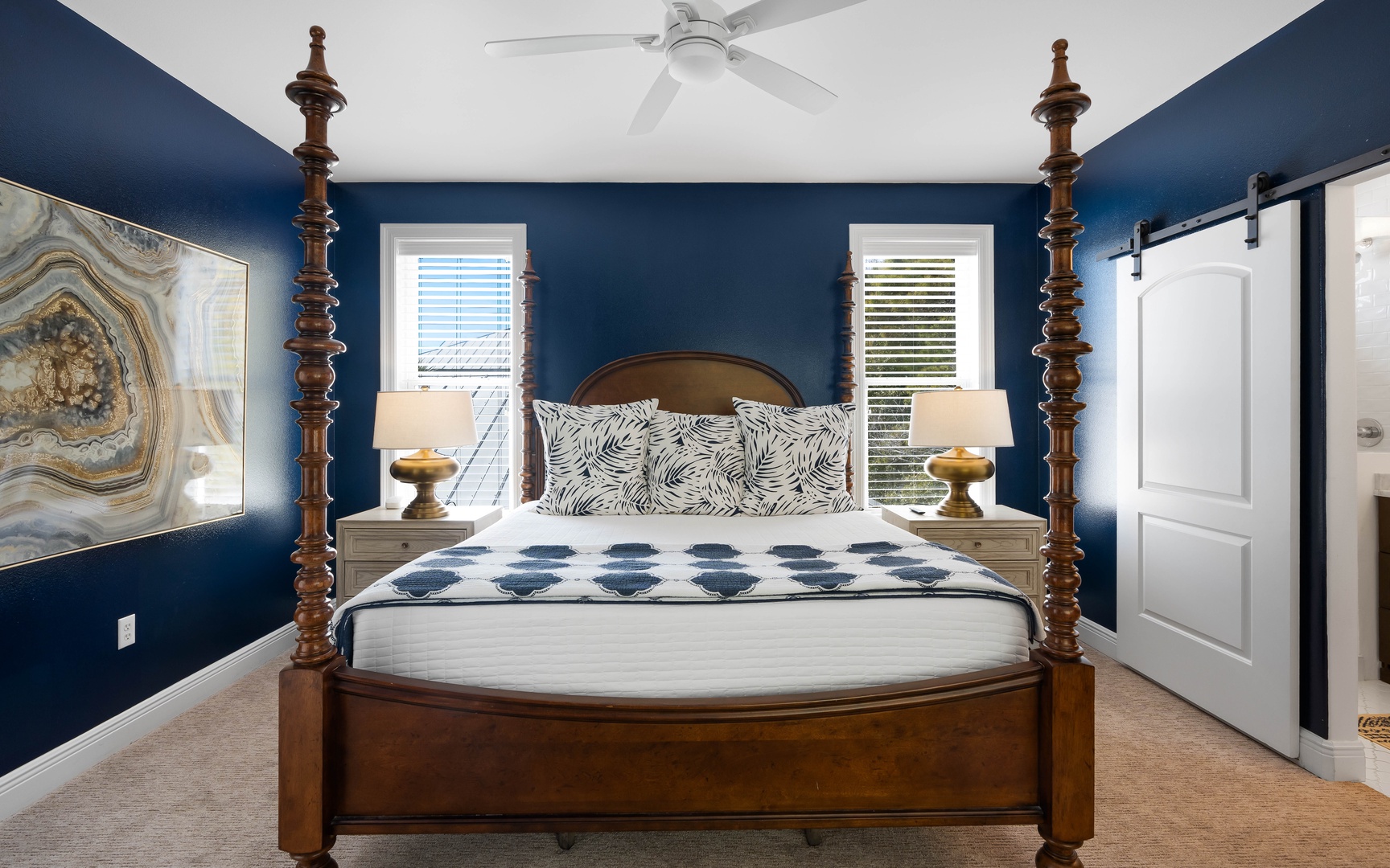 Unwind in your elegant bedroom featuring a stunning four-poster bed, rich navy walls, and coastal artwork that creates a sophisticated coastal retreat.