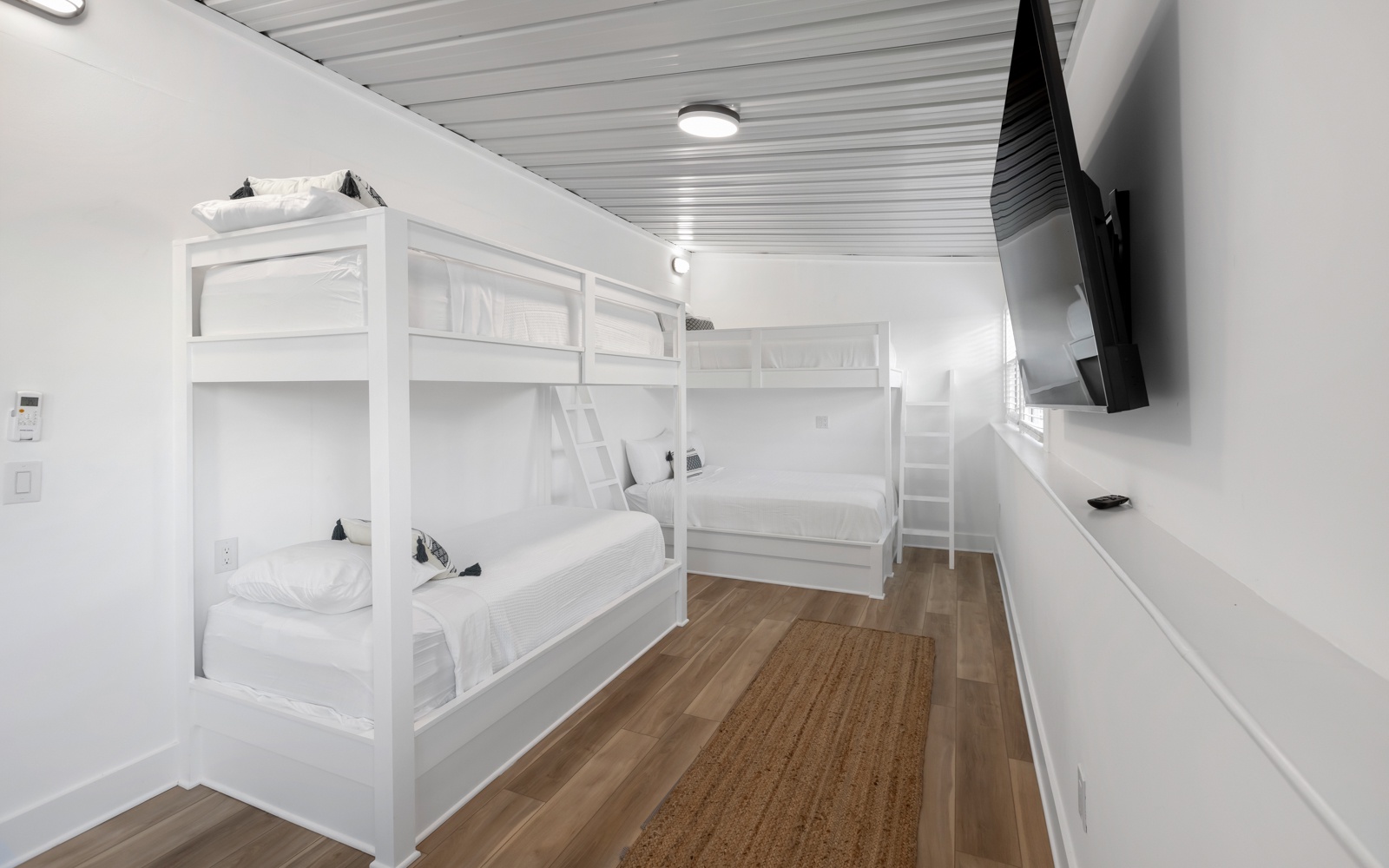 Your cozy bunk room features built-in white beds with crisp linens and a wall-mounted TV for entertainment.