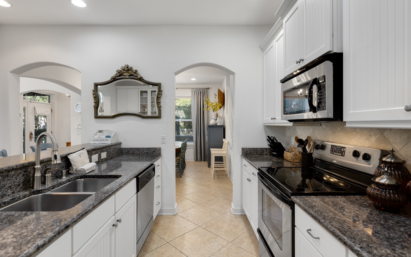 Your fully-equipped kitchen awaits with granite counters, stainless appliances, and elegant archways leading to bright living spaces.