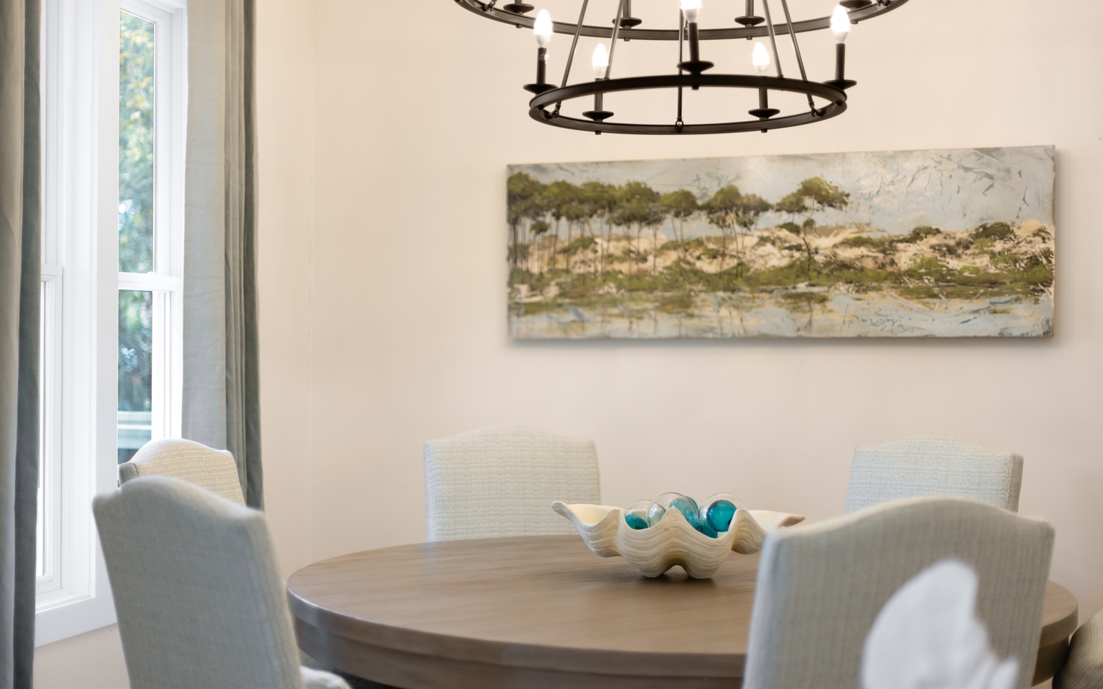 Your elegant dining space features a round table perfect for intimate meals, complemented by soft natural light.