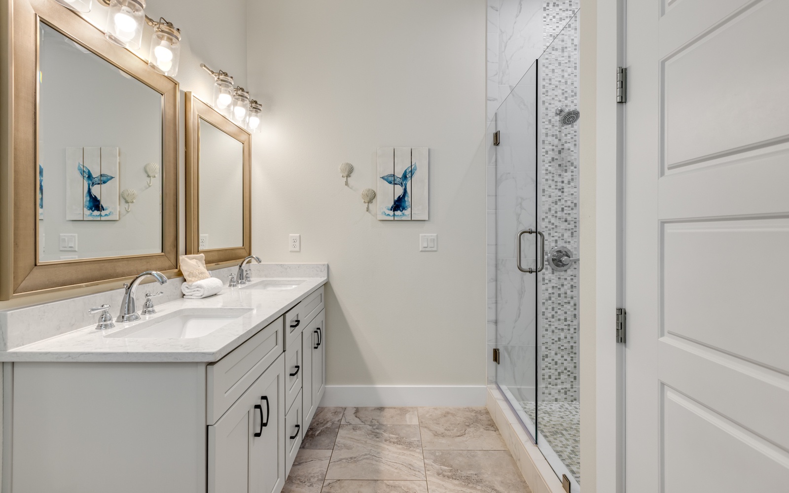 Your elegant ensuite bathroom features dual vanities with marble countertops and a stunning glass-enclosed shower with mosaic tile accents.
