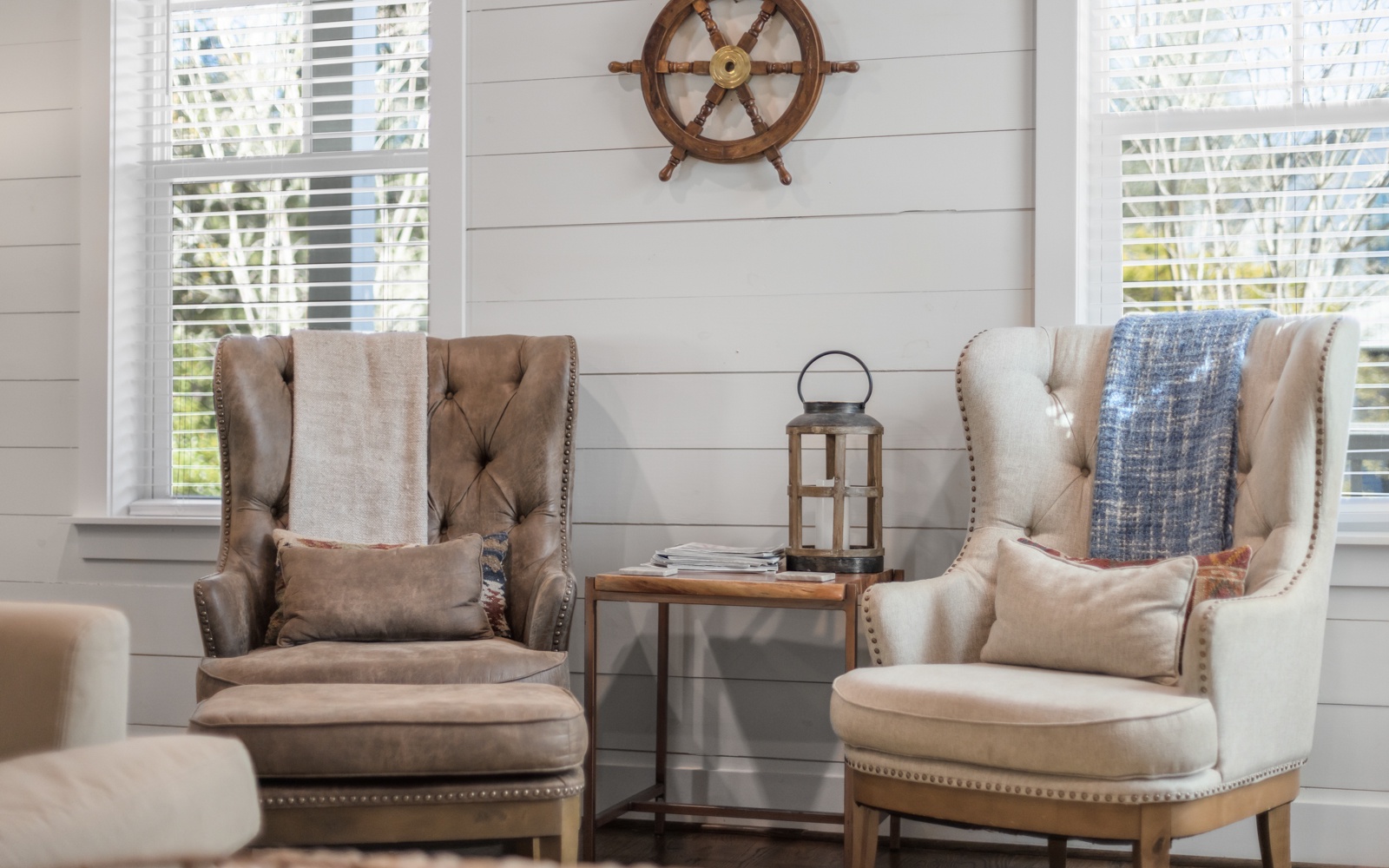 Sink into plush wingback chairs by bright windows where natural light and coastal charm create your perfect reading retreat.