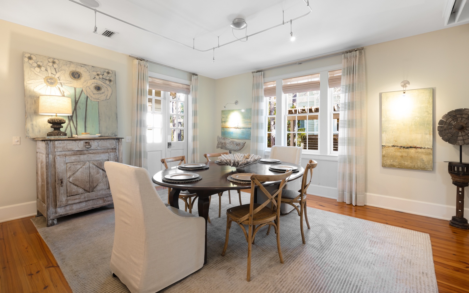 Gather around this elegant oval table where natural light streams through French doors, creating the perfect setting for your memorable meals.
