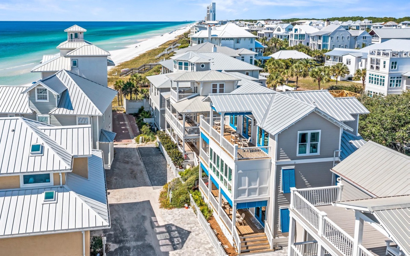 Stunning aerial view of coastal vacation homes with pristine turquoise waters and white sand beach stretching endlessly along this picturesque shoreline community.