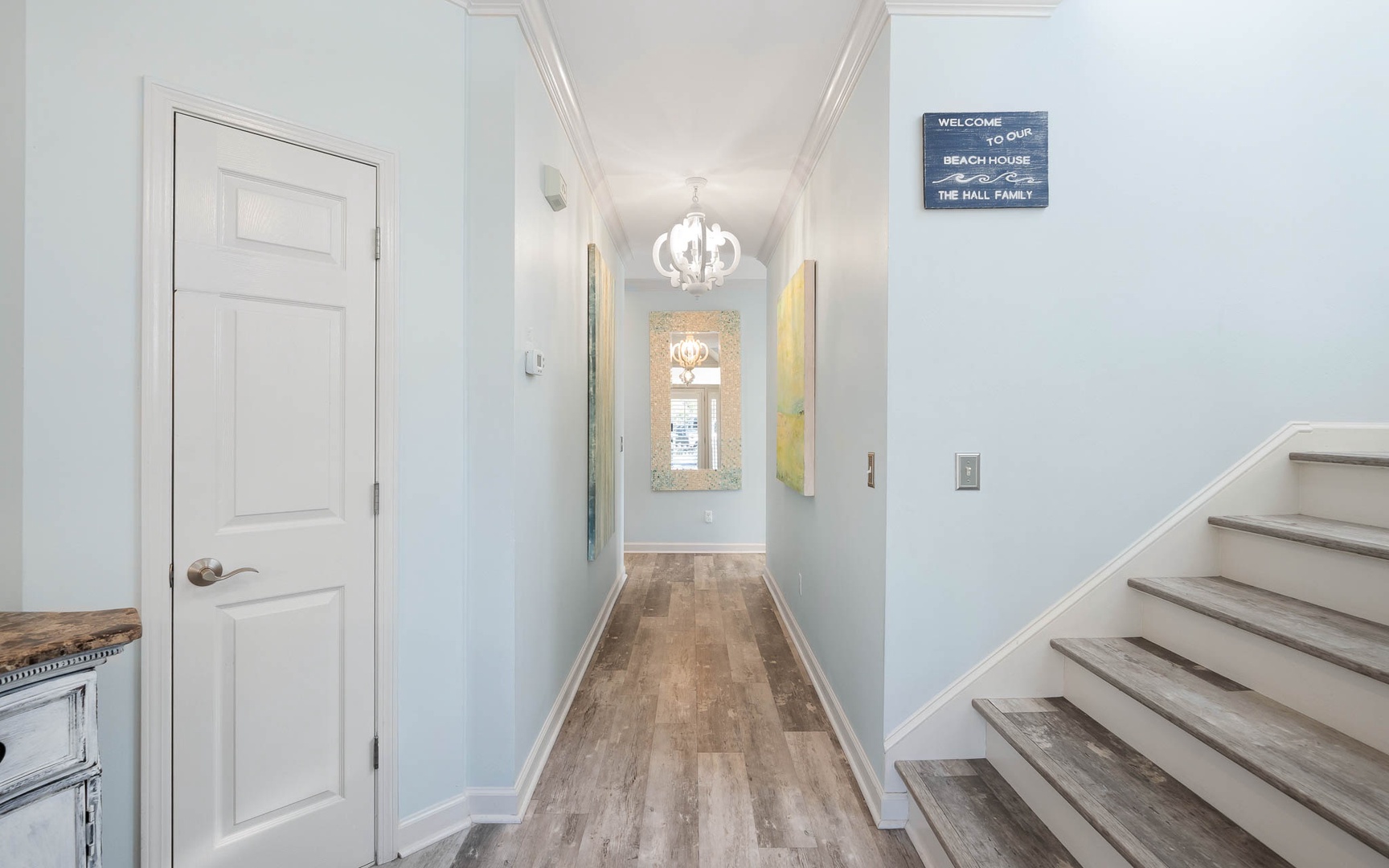 Step into your elegant beach house hallway, where coastal charm meets sophisticated design with gleaming hardwood floors and welcoming touches.