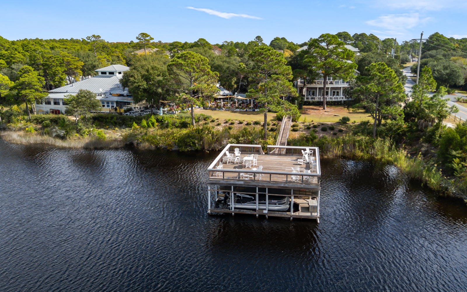 Aerial view showcases the waterfront property with private dock and boat lift on tranquil waters surrounded by lush coastal landscape.