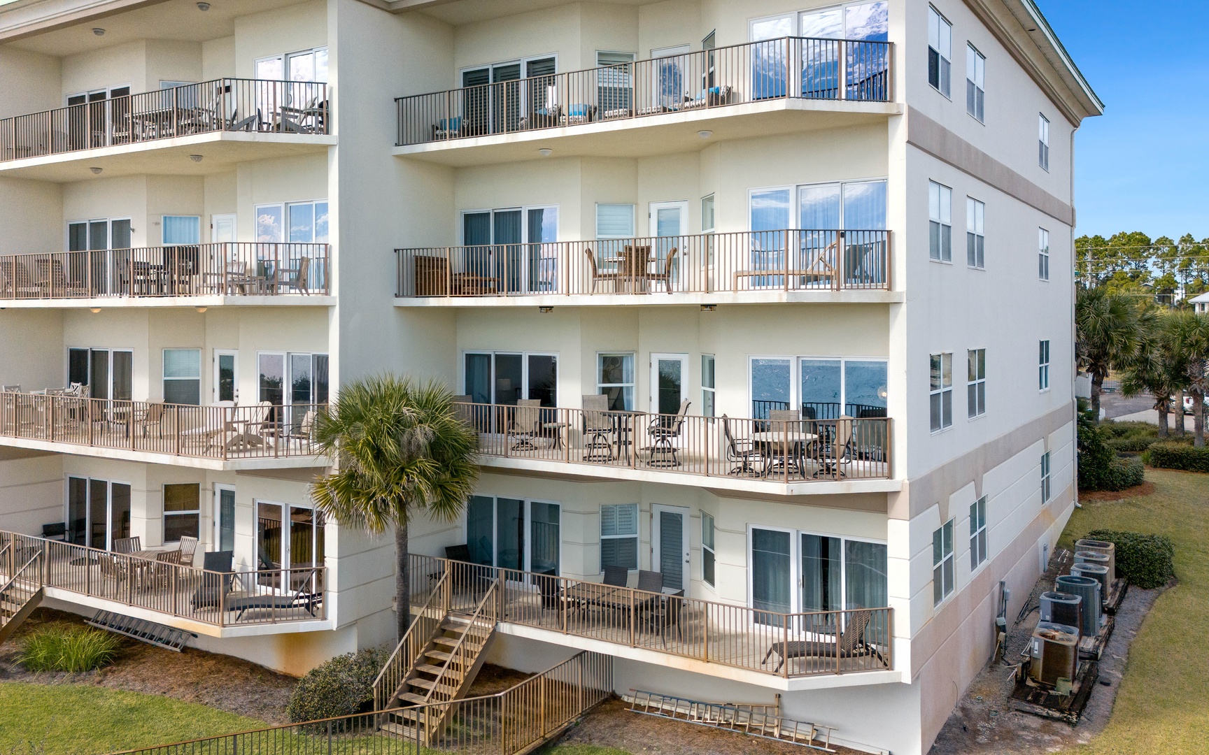 Modern beachside building with multiple balcony levels and tropical landscaping in a peaceful resort setting.