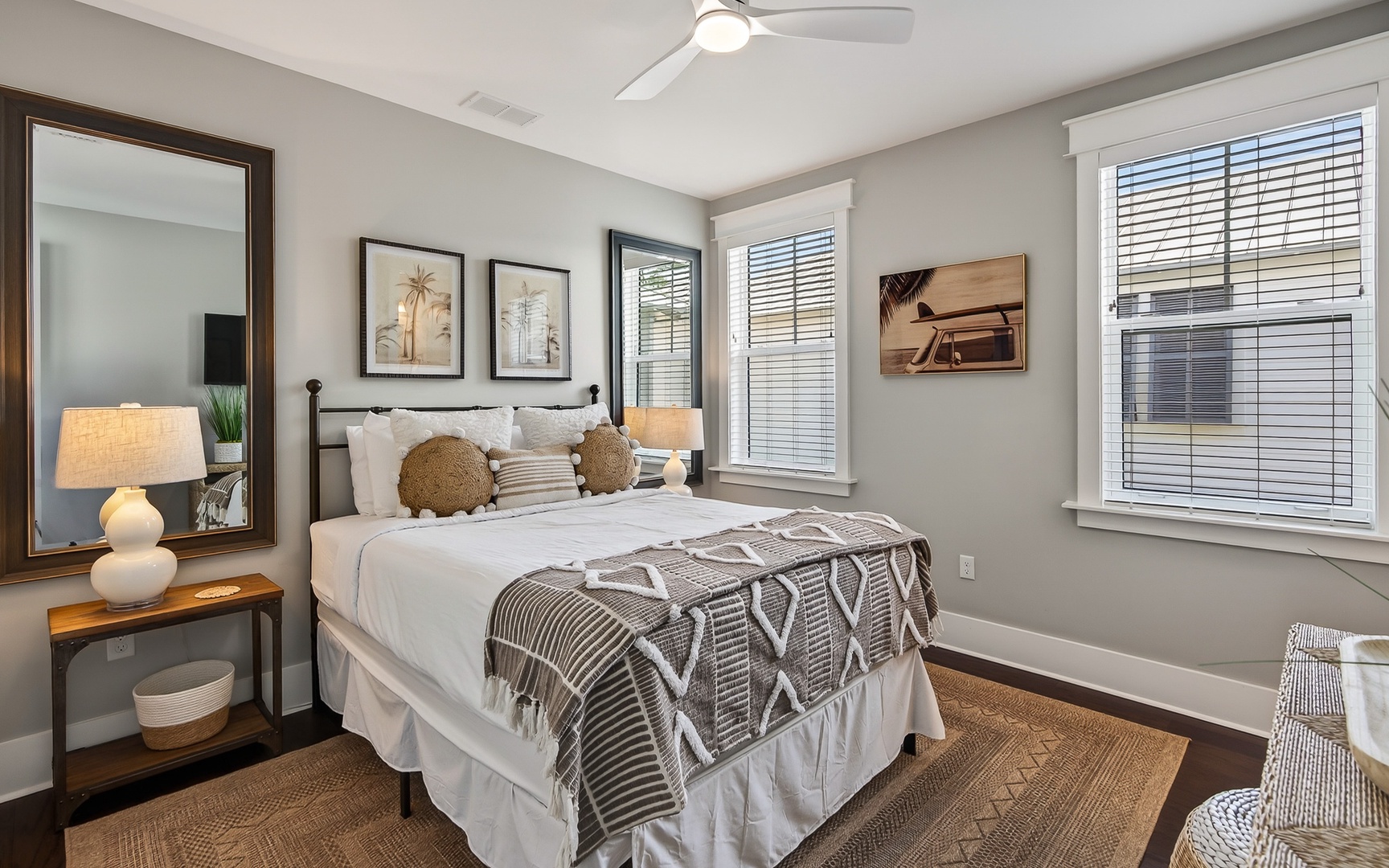 Sink into crisp white linens and soft textures in your peaceful retreat, where natural light filters through blinds and coastal artwork sets a relaxing tone.