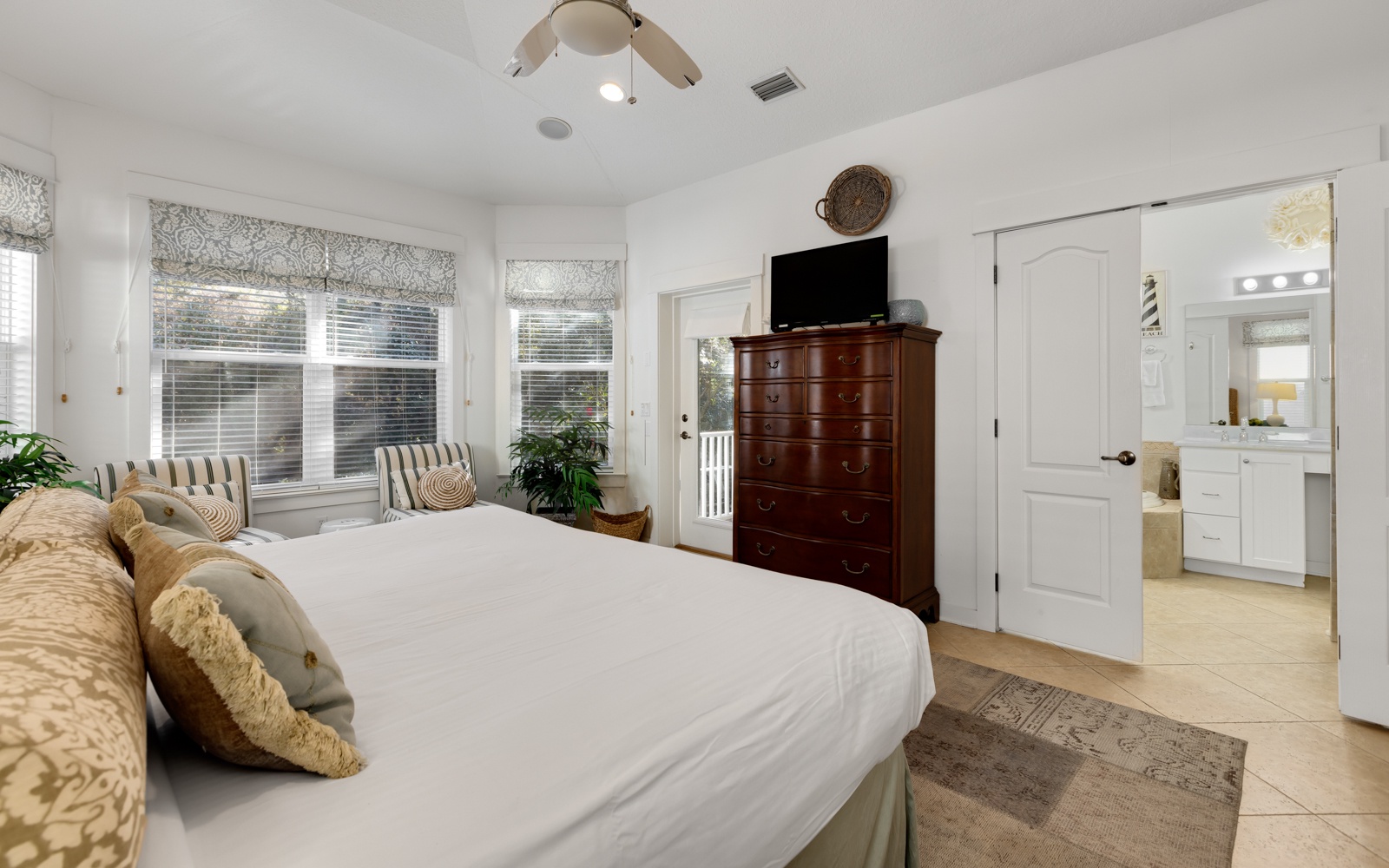 Drift off to sleep in your serene master bedroom, complete with cozy linens and warm natural light streaming through patterned window shades.