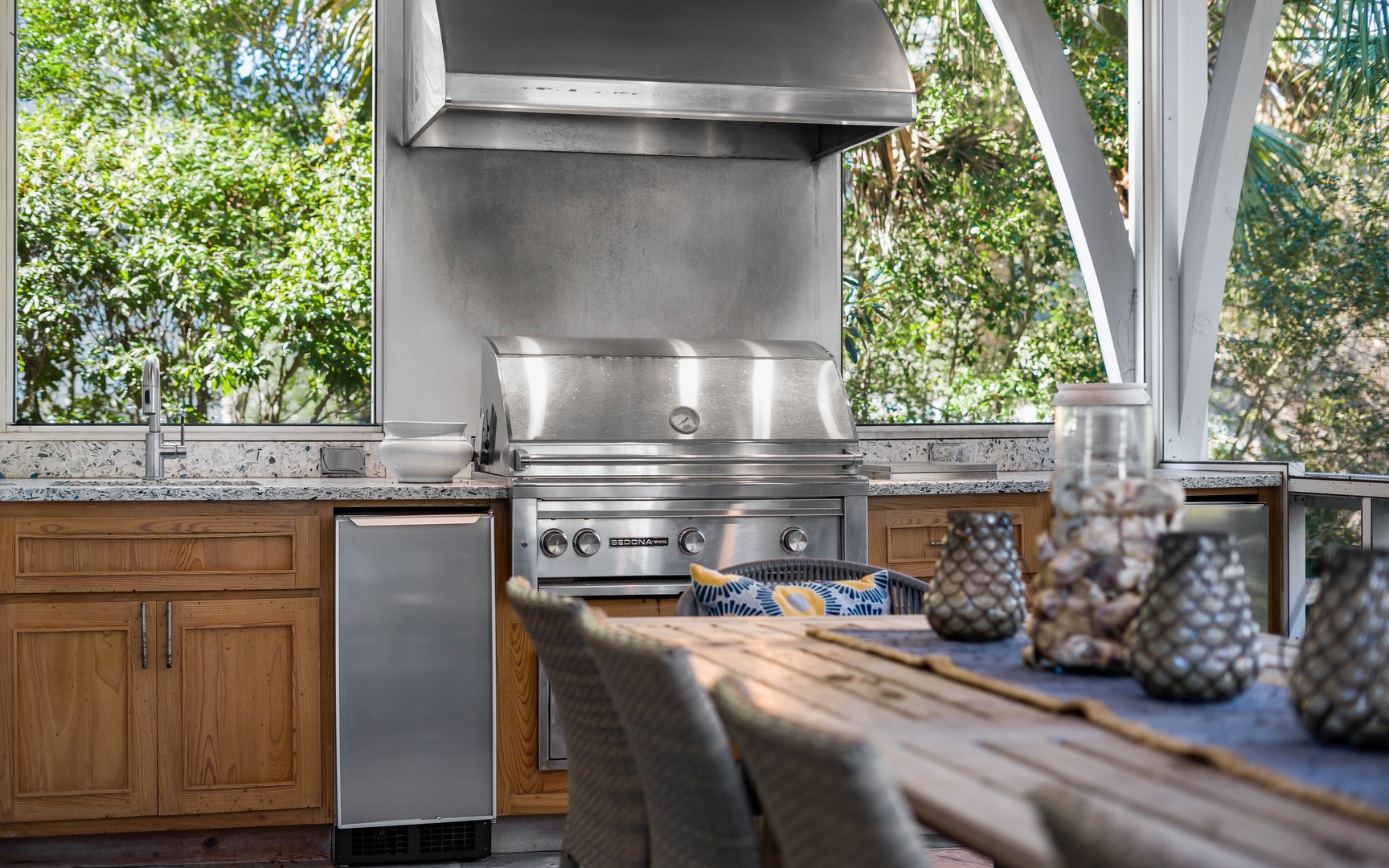 Your private outdoor kitchen awaits with professional-grade grilling and granite counters surrounded by lush greenery.
