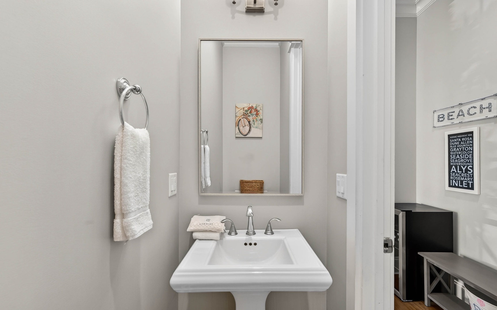 Refresh in your stylish powder room with coastal charm, featuring crisp white fixtures and thoughtful beach-themed touches.