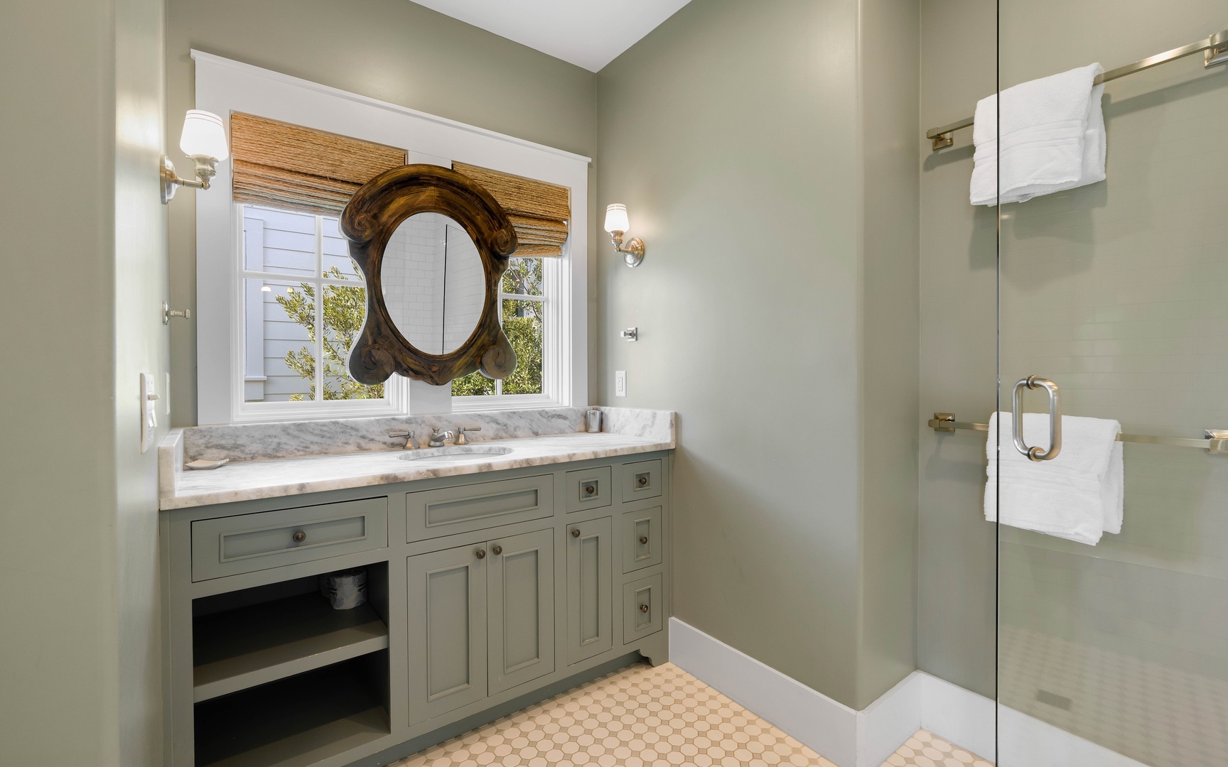 Unwind in your elegant bathroom featuring marble countertops, a glass shower, and thoughtful touches like fresh towels.