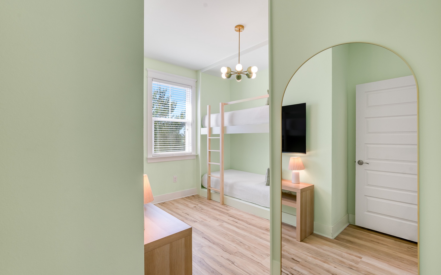 Your kids will love this cheerful bunk room with soft green walls, cozy lighting, and space to play and rest.