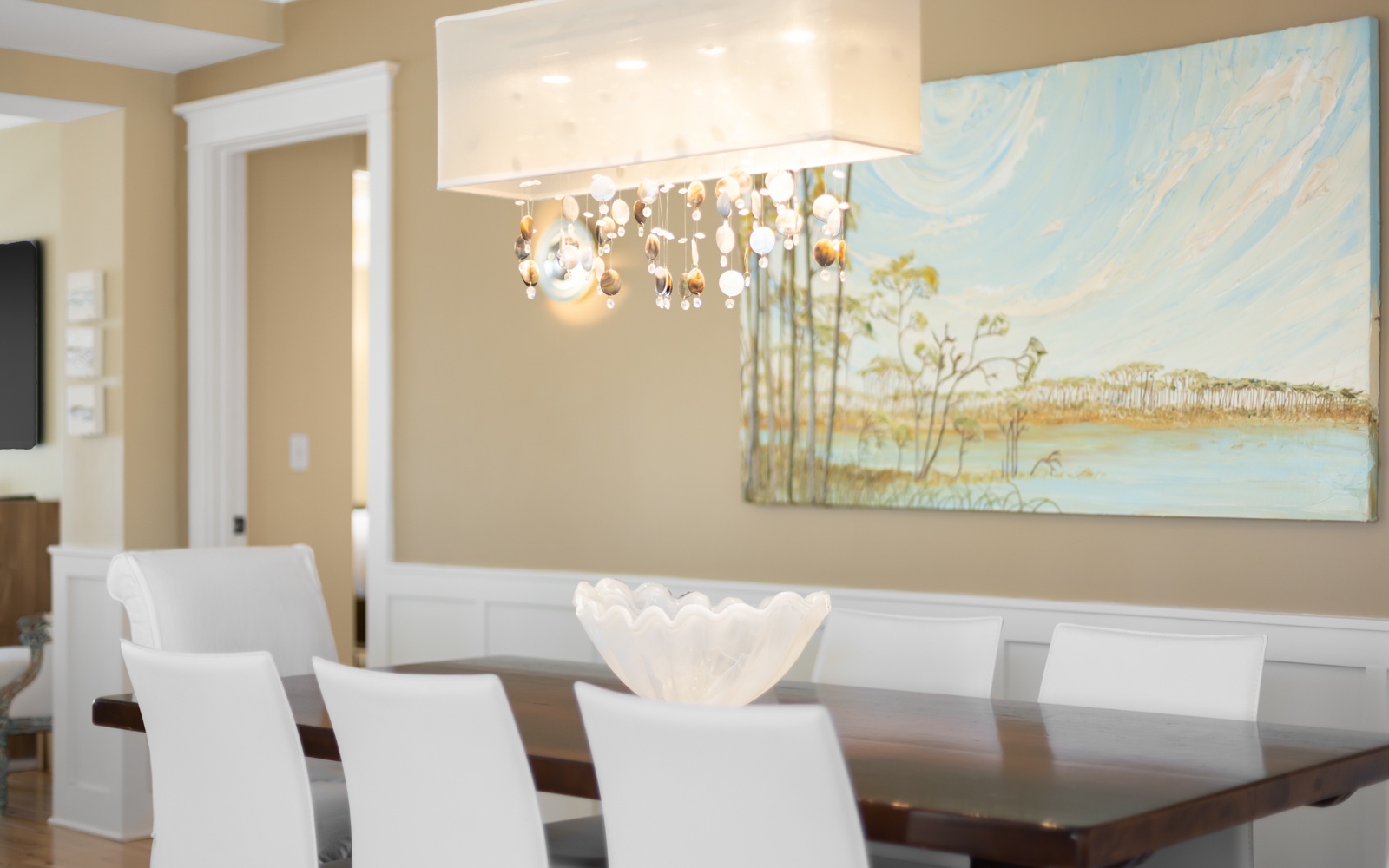 Gather around your elegant dining table where thoughtful touches and beautiful artwork create the perfect atmosphere for memorable meals together.