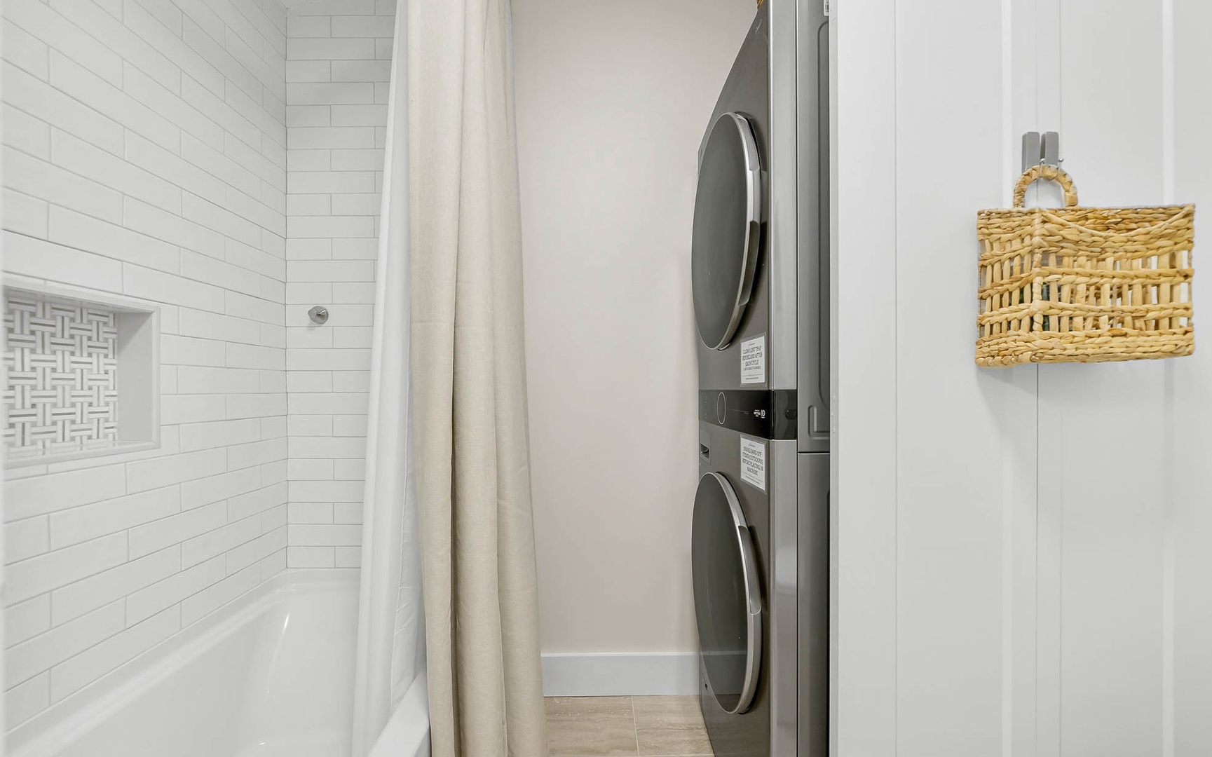 Your private bathroom features a sleek shower with modern subway tile and convenient stacked washer-dryer for effortless laundry during your stay.