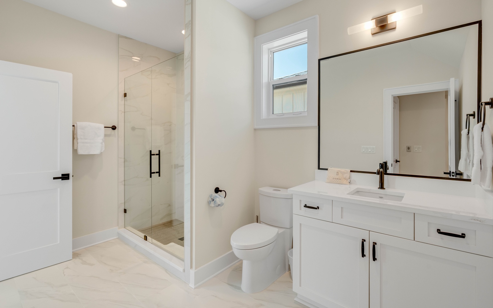 Step into your spa-like bathroom with sleek white vanity, spacious glass shower, and elegant finishes throughout.
