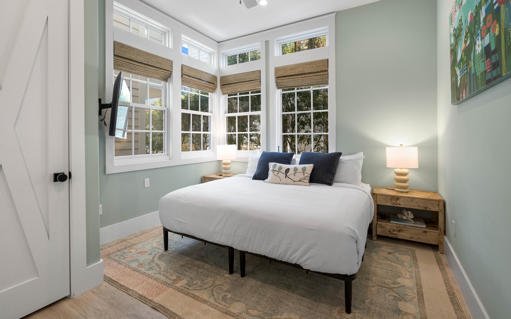 Drift into peaceful dreams in this charming bedroom with soft mint walls and abundant natural light from corner windows.