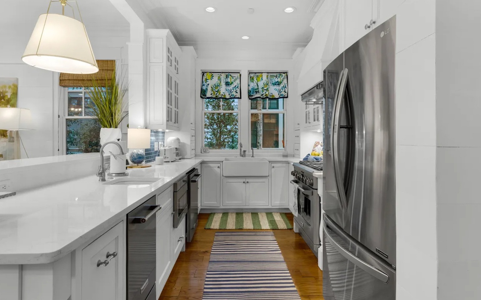 Prepare meals in this bright, modern kitchen featuring stainless steel appliances, quartz countertops, and abundant natural light from cheerful garden windows.