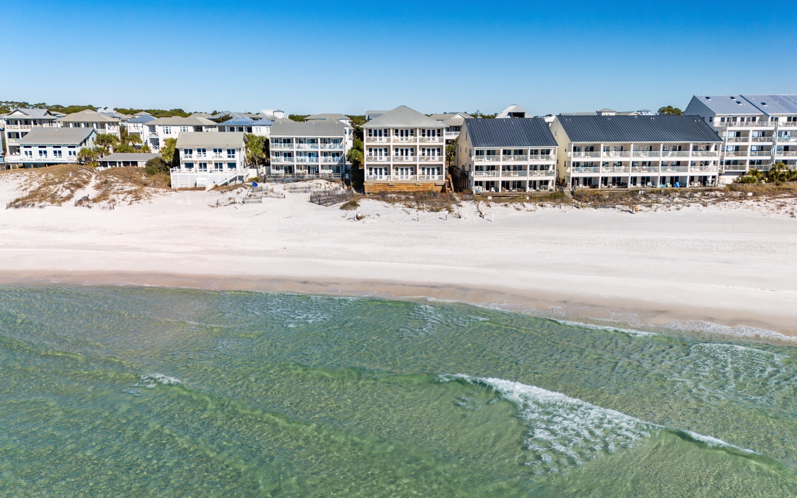 Beachfront property complex with direct access to pristine white sand and crystal-clear emerald waters.