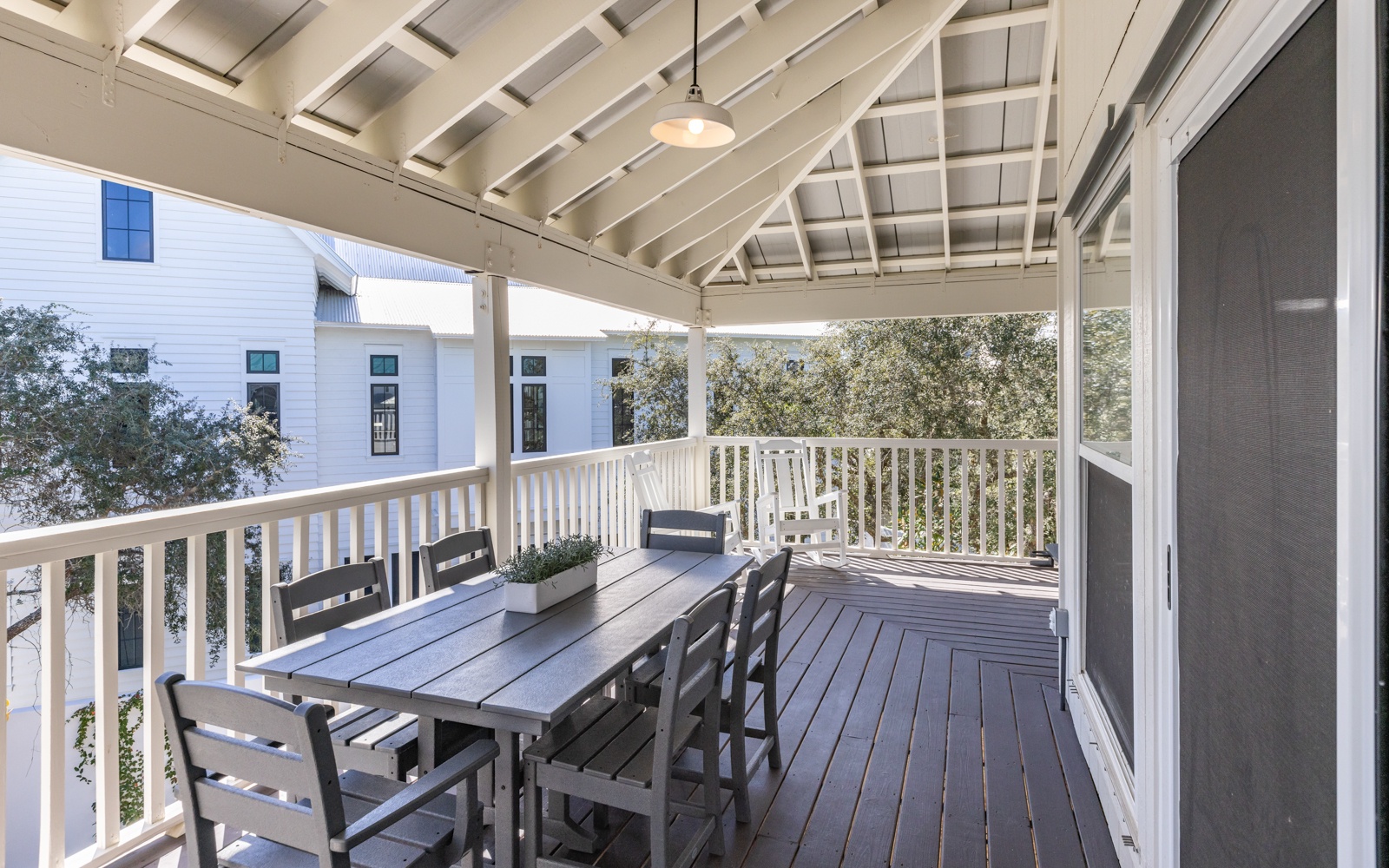 Your covered terrace offers perfect dining space with charming wooden beams above and peaceful neighborhood views beyond.