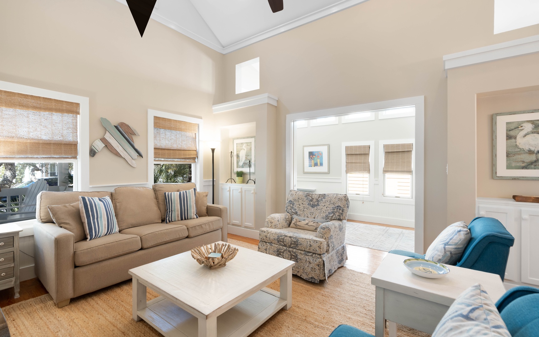 Relax in your bright, airy living room with plush seating and coastal charm. Natural light fills the space through elegant windows.