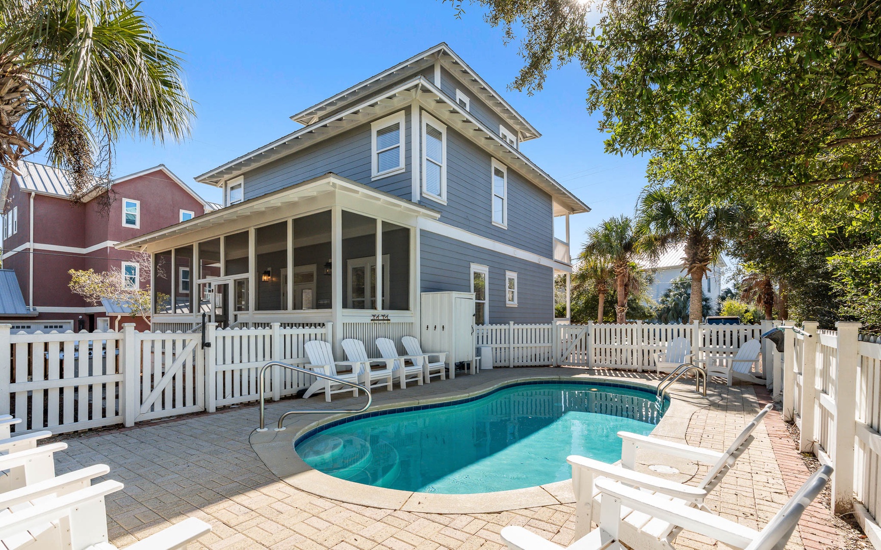 Charming coastal home with private pool and spacious wrap-around porch surrounded by tropical landscaping.