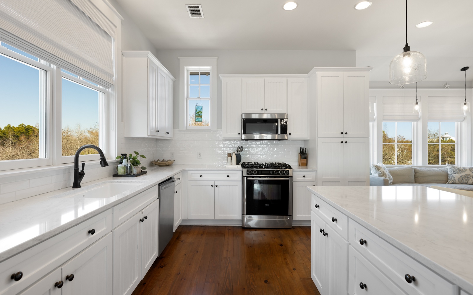 You'll love preparing meals in this bright, modern kitchen with gleaming white cabinets, spacious countertops, and premium appliances bathed in natural light.