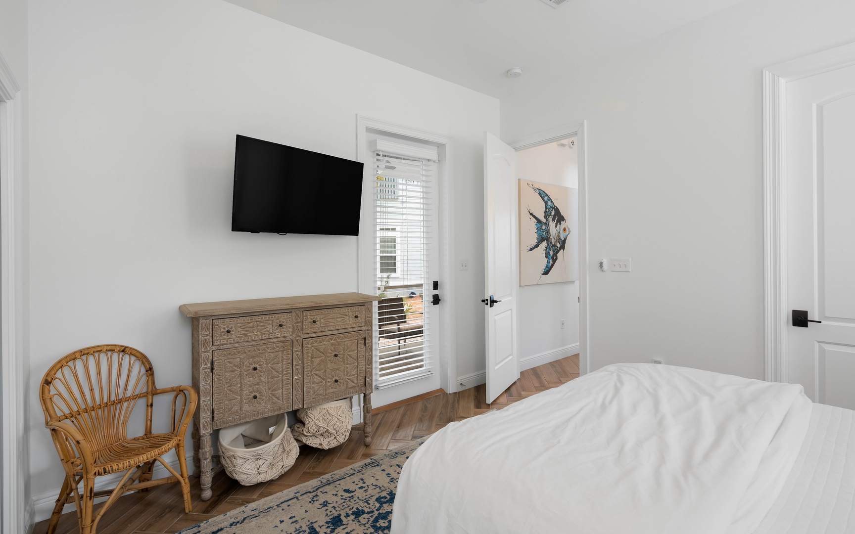 Your stylish bedroom features a mounted TV, rustic dresser, and charming wicker chair for cozy mornings.