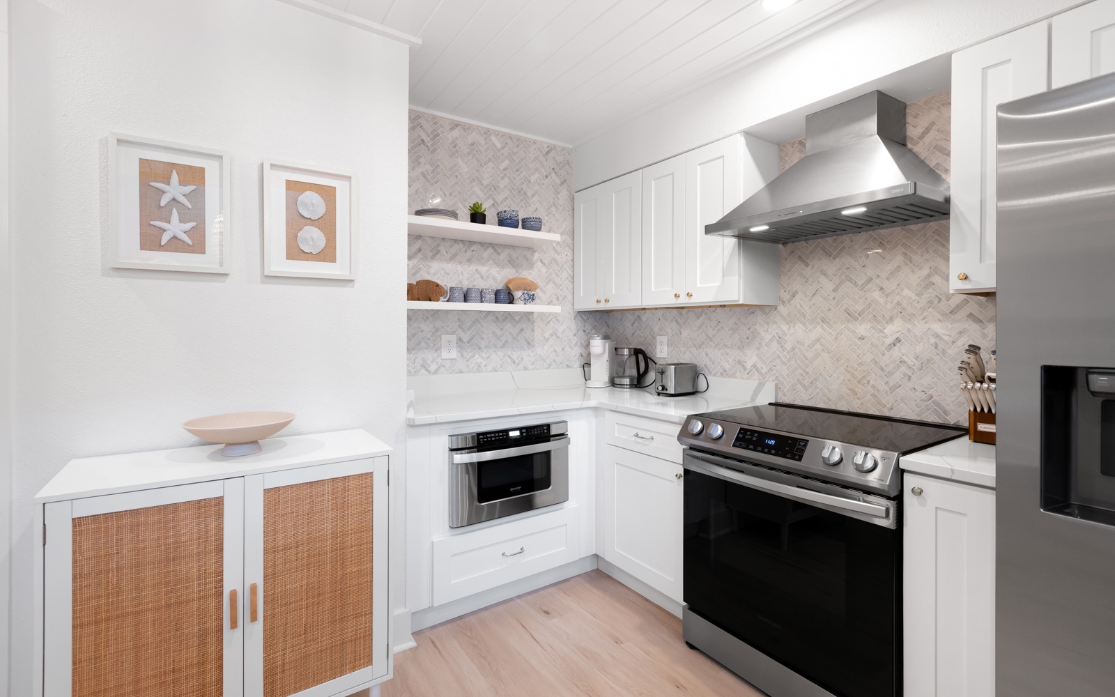 Your stylish kitchen features modern appliances, gleaming white cabinets, and herringbone marble backsplash—perfect for preparing memorable meals during your stay.
