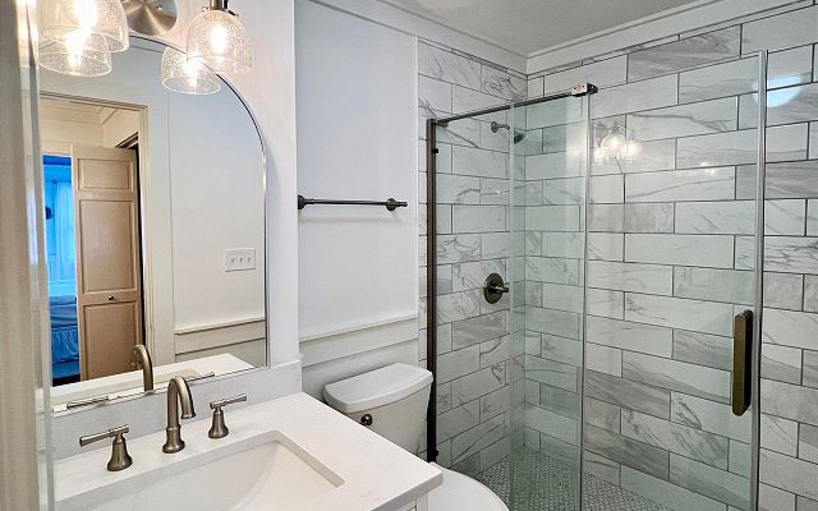 Luxurious marble bathroom with glass shower, elegant vanity, and stylish lighting awaits your relaxing getaway.