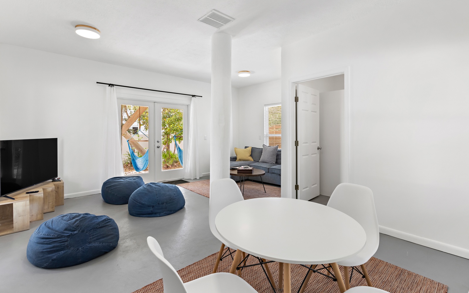 Relax in your modern open-plan living space with cozy navy bean bags, sleek dining table, and bright French doors opening to your private patio.
