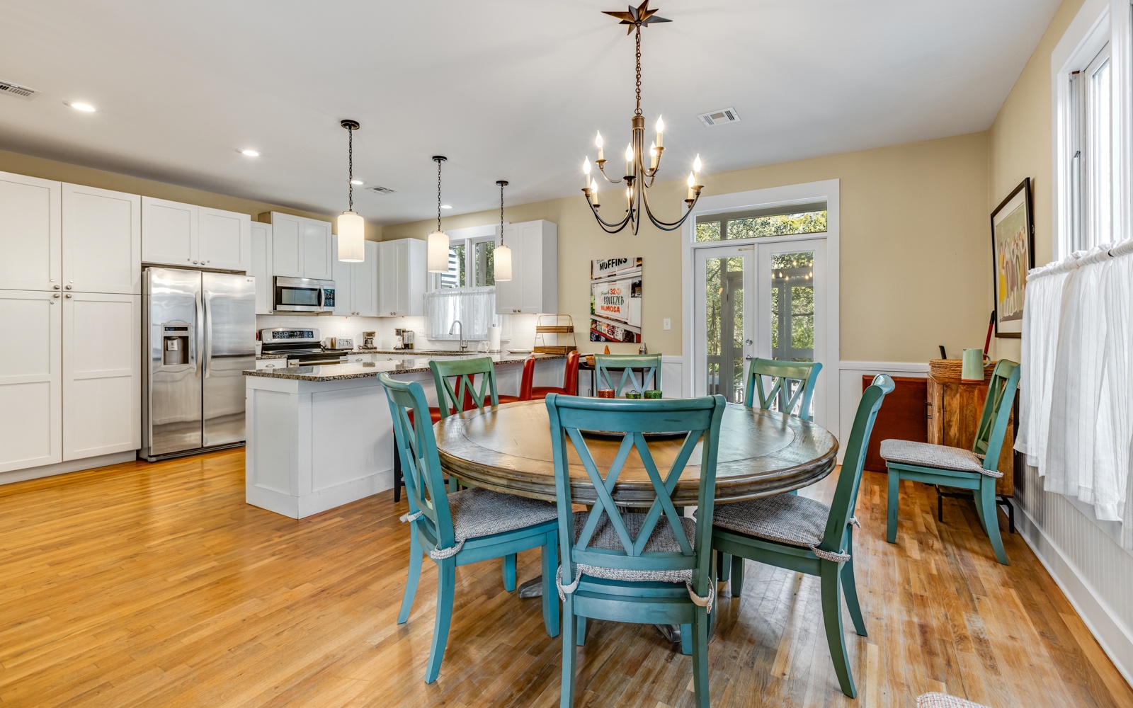 Your open-concept kitchen and dining space features modern appliances, granite countertops, and charming turquoise chairs around a spacious round table.