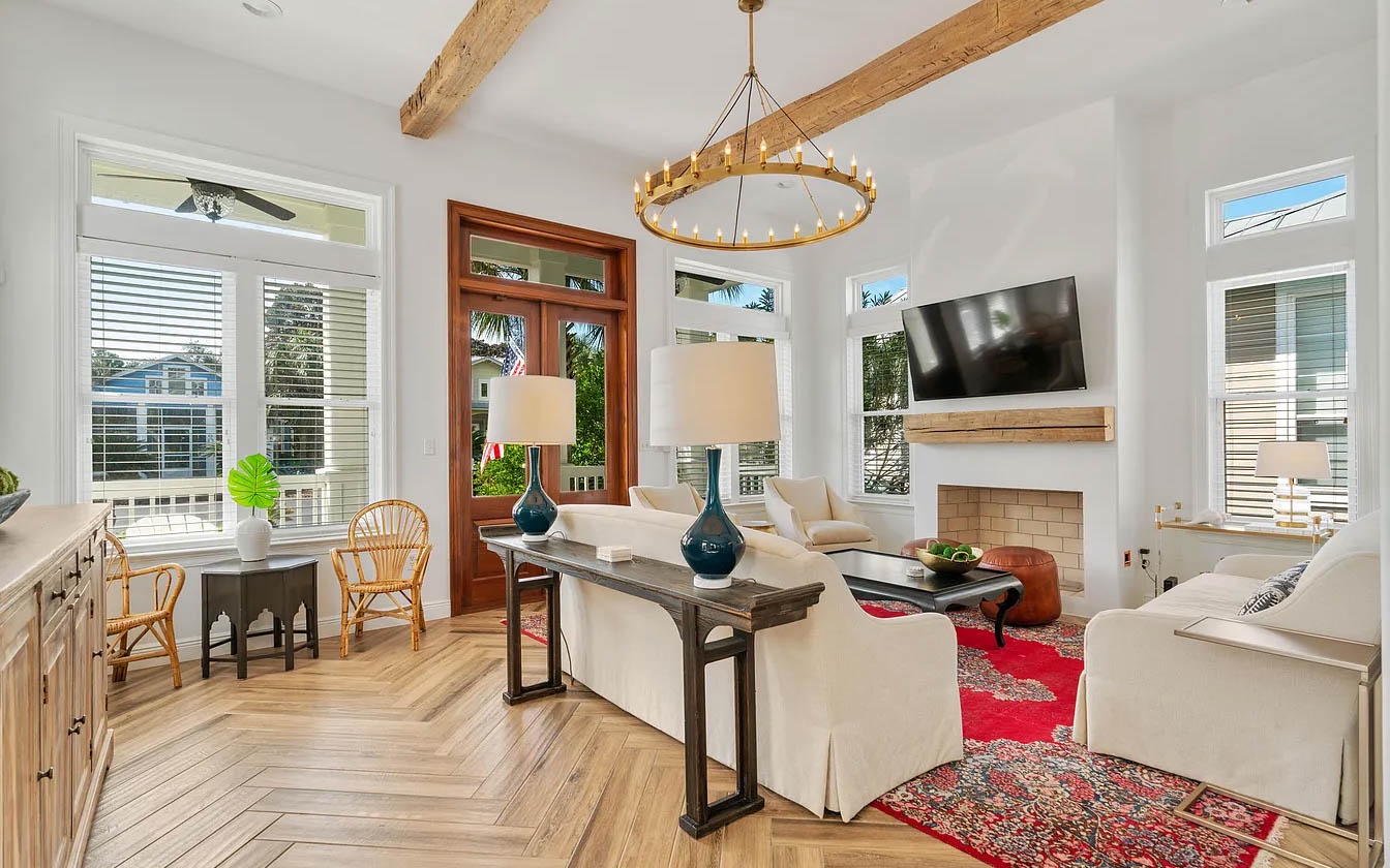 Relax in your elegant living space where exposed beams and golden chandelier create warmth above plush seating.