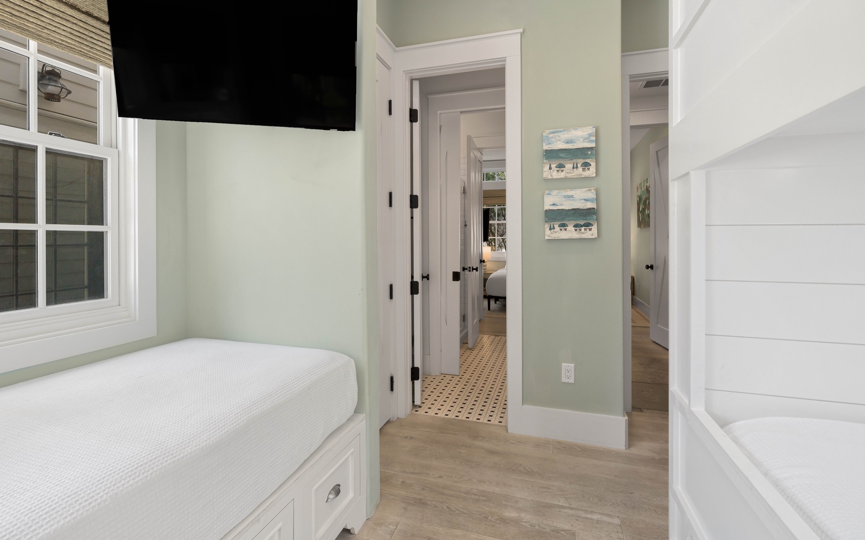 Your cozy bedroom features a built-in window seat perfect for morning coffee, with charming coastal artwork and warm wood floors throughout.