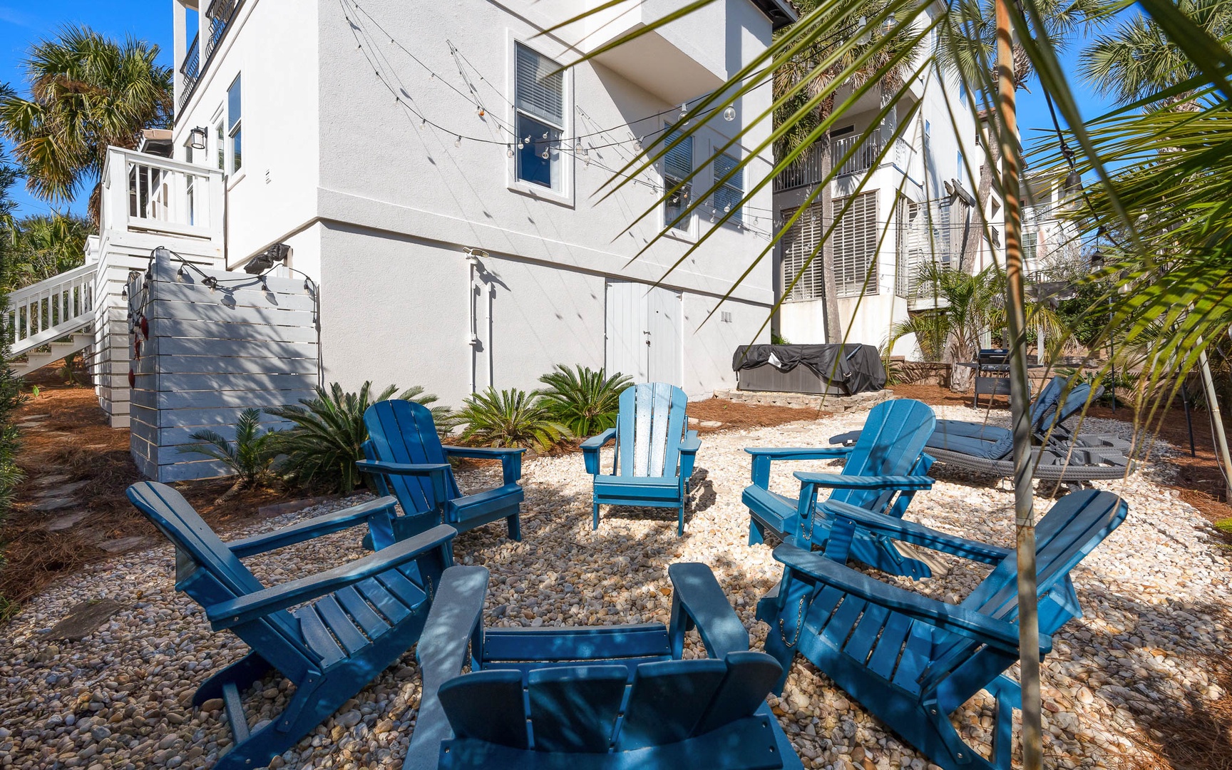 Sink into vibrant blue Adirondack chairs in your private tropical retreat, where swaying palms and coastal breezes create the perfect outdoor escape.
