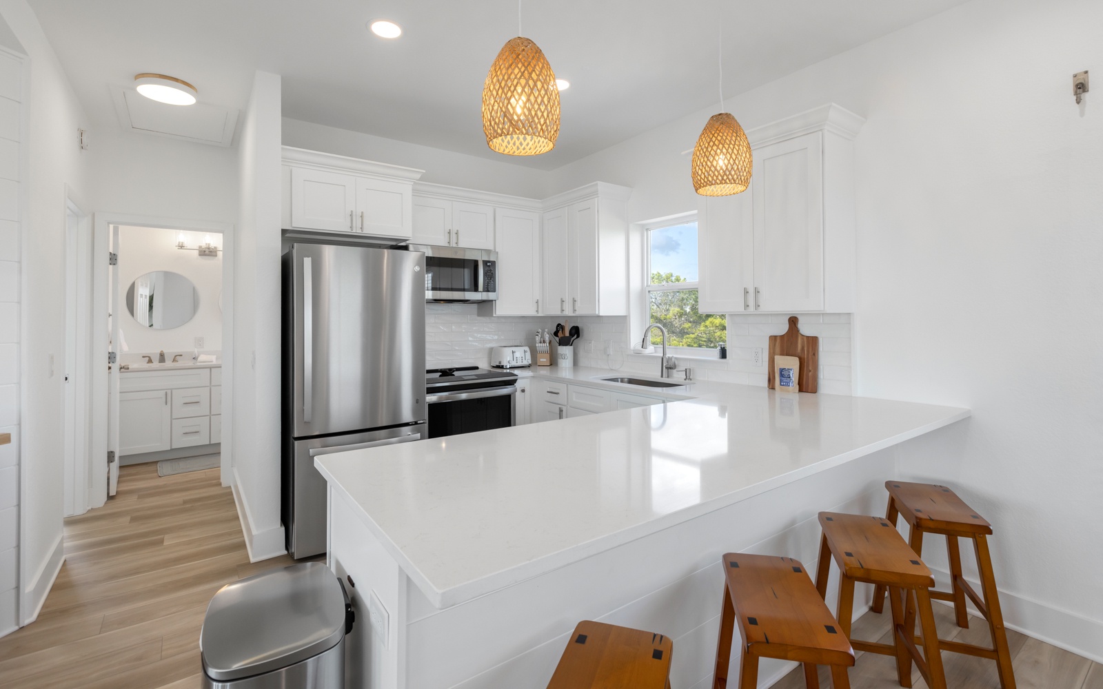 Your bright, modern kitchen features sleek white cabinetry, stainless steel appliances, and a spacious island perfect for morning coffee or casual dining.
