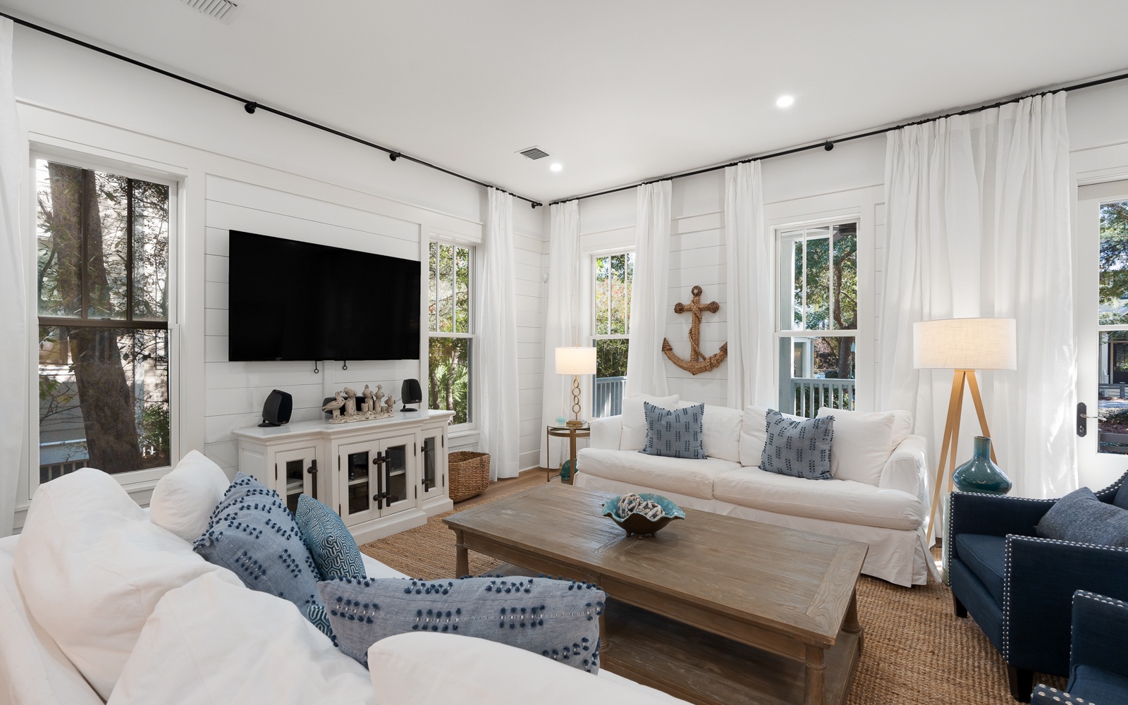 Sink into coastal comfort in this bright living room with nautical touches and natural light streaming through windows.
