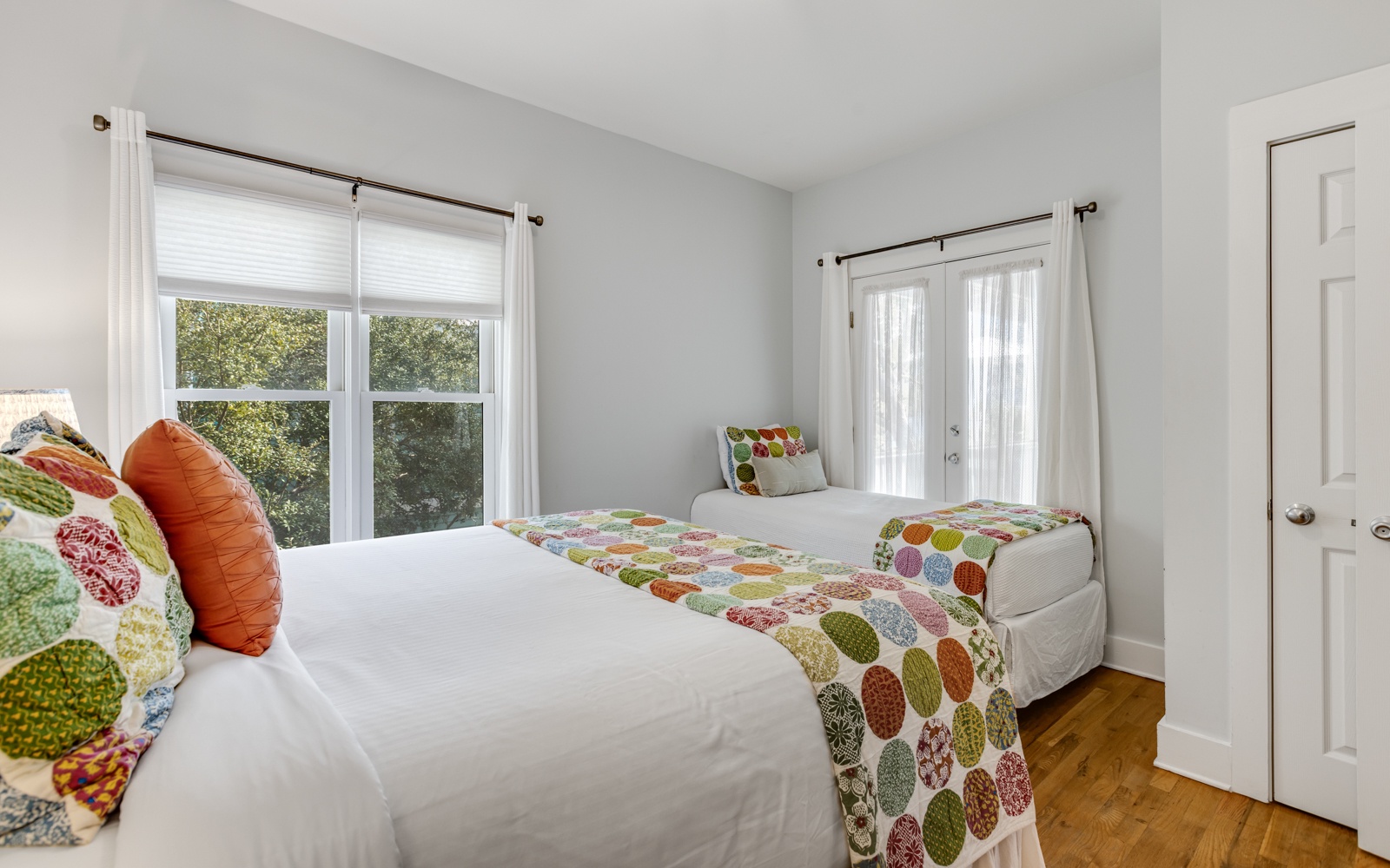 Rest peacefully in your bright twin bedroom with cheerful patterned linens and garden views through large windows.