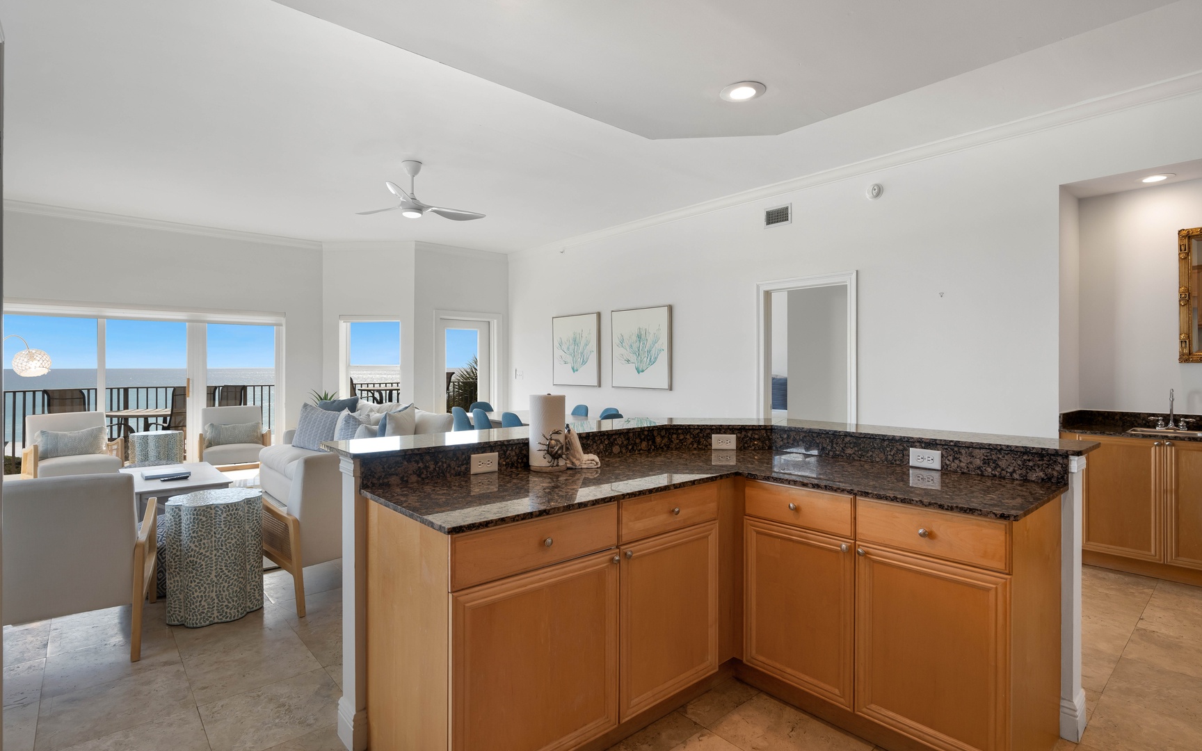 Your open kitchen flows seamlessly into the living area with ocean views streaming through floor-to-ceiling windows.