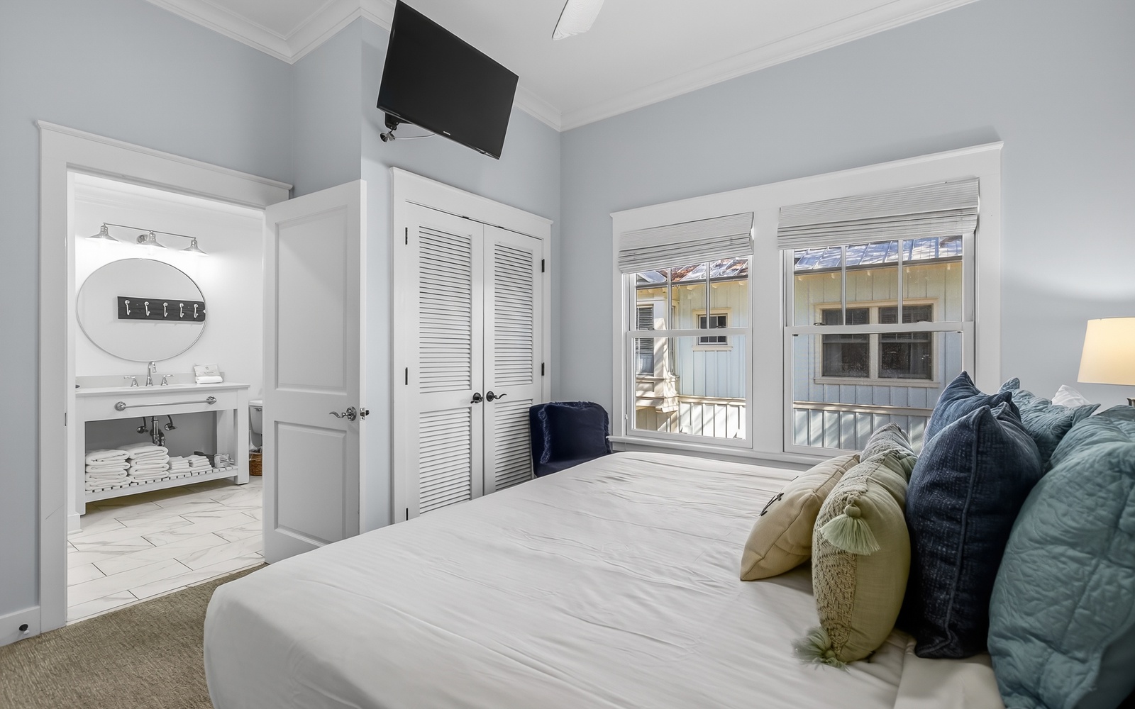 Drift off in this serene bedroom with crisp linens, en-suite bath, and charming windows overlooking peaceful surroundings.