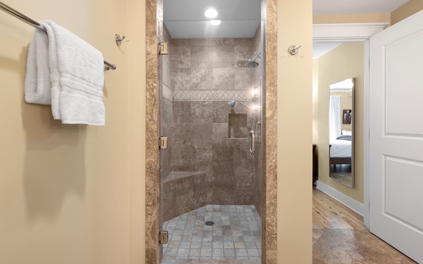 Step into your luxurious glass-enclosed shower with elegant stone tile and rainfall showerhead for ultimate relaxation.