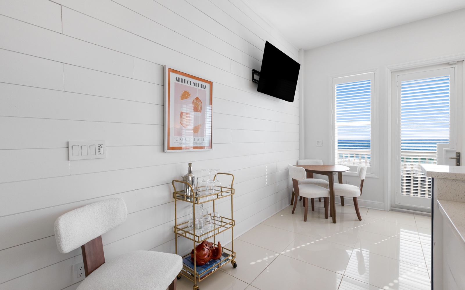 Your bright, modern dining space features clean white shiplap walls and a stylish round table where you'll enjoy meals with natural light streaming through large windows.