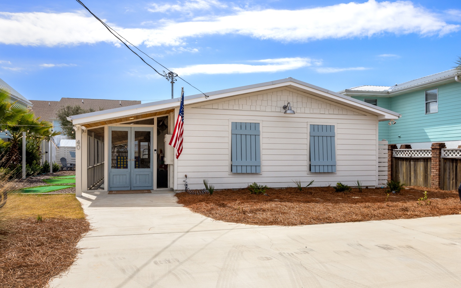 Charming beachside cottage with blue shutters and welcoming front porch in a quiet coastal neighborhood.