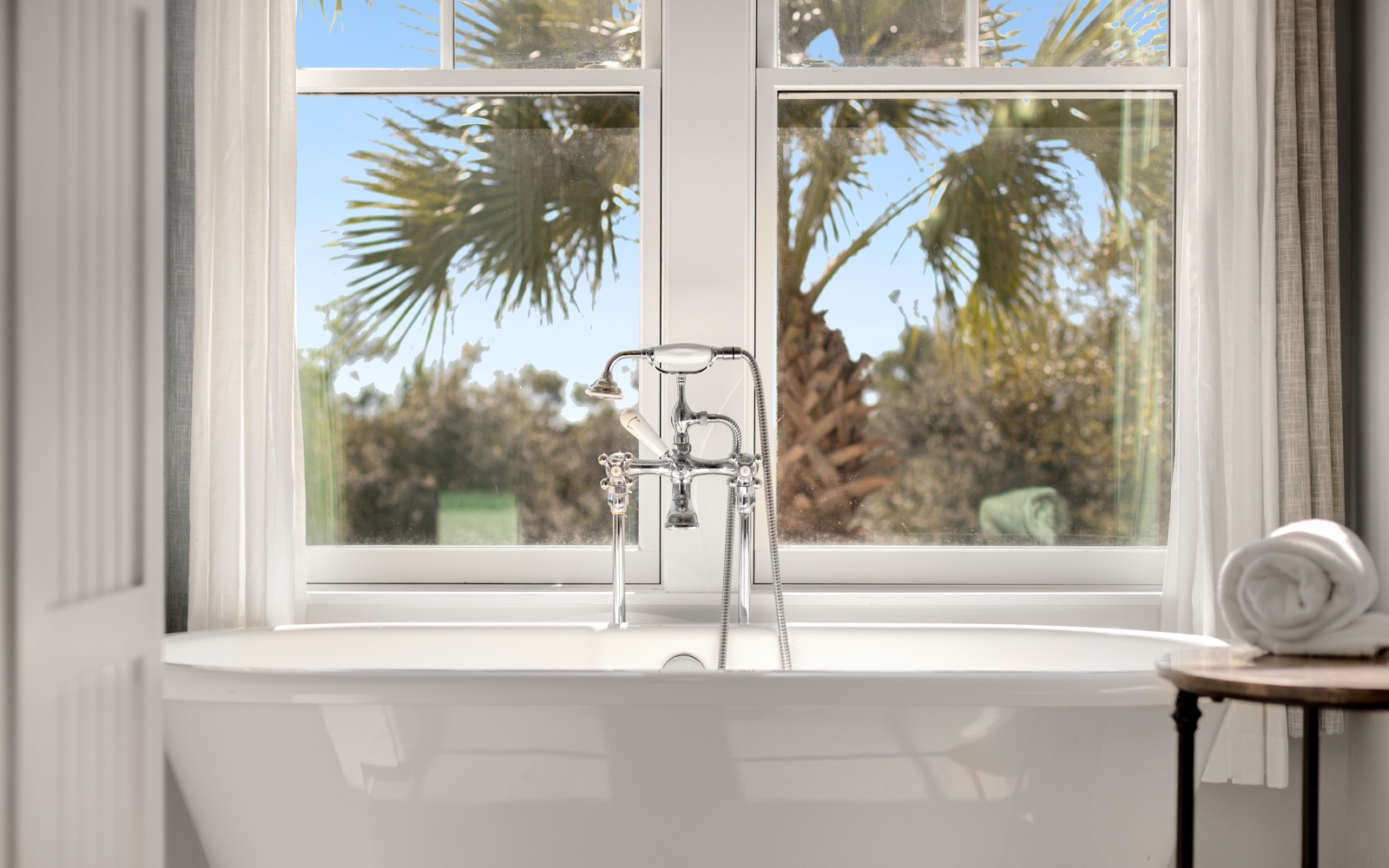 Soak in your elegant freestanding tub while gazing at swaying palms through bright windows—your perfect tropical retreat awaits.