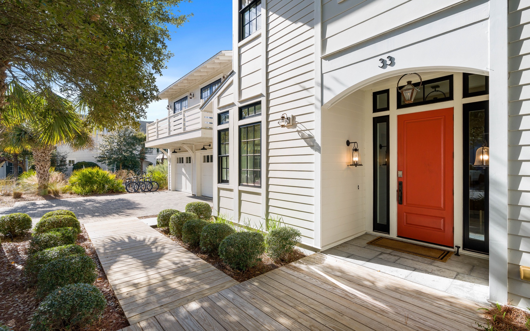 A welcoming property entrance with distinctive orange door and elegant landscaping marks your arrival destination.