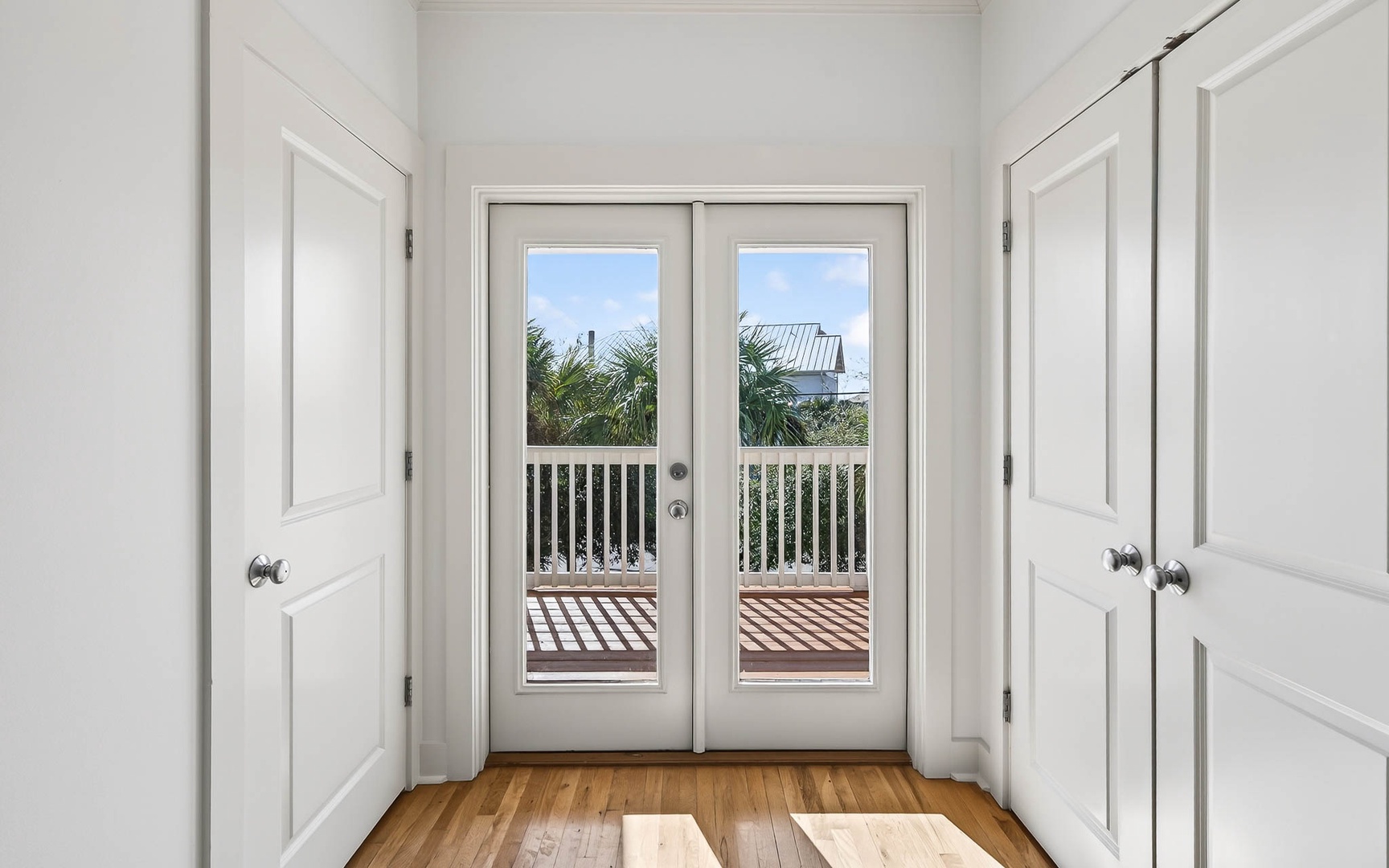 Step through these elegant French doors to your private balcony, where tropical palms and blue skies create the perfect backdrop for morning coffee.